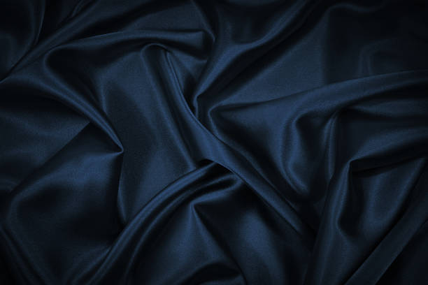 istock Black blue abstract background. Dark blue silk satin texture background. Beautiful wavy soft folds on the surface of the fabric. 1293604429