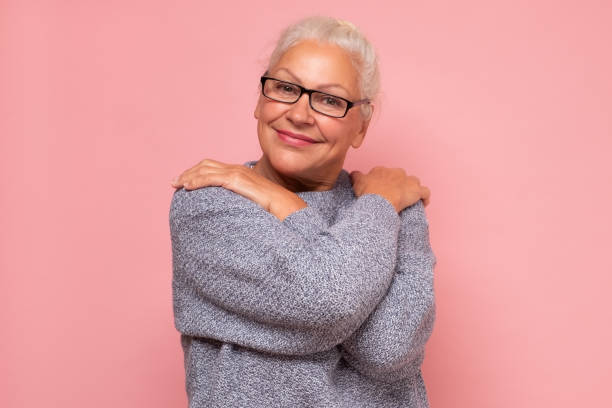 Elderly mature lady in glasses embracing herself Self love, joy and happiness concept. Elderly mature lady in glasses embracing herself hugging self stock pictures, royalty-free photos & images