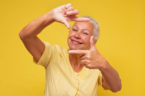 istock Senior woman looking at camera and gesturing finger frame 1293607804