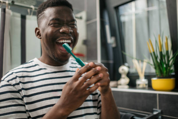 istock Young African American man brushing his teeth at home 1293607900