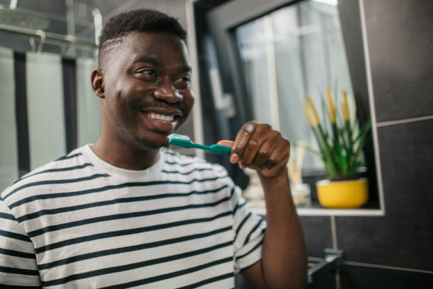 istock Young African American man brushing his teeth at home 1293607963