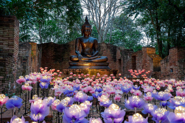 lighting decorate buddha statue lighting lotus flower decorated in front of Ayuthaya era Buddha statue with old ruin wall at Ratchaburi, Thailand ratchaburi province stock pictures, royalty-free photos & images