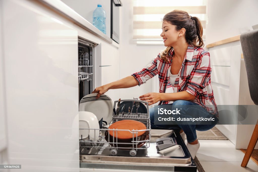 Diligent housewife putting dishes into dishwasher. Dishwasher Stock Photo