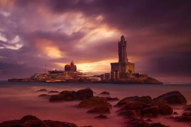 Photo of Kanyakumari - Vivekananda Rock Memorial Thiruvalluvar Statue in the evening with a colorful and cloudy sky background.