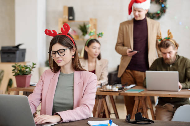 istock Young female office manager networking by table in office on Christmas day 1293617089