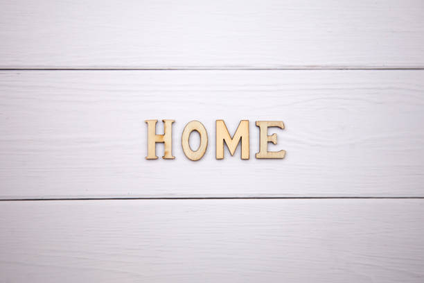 Decorative letters forming word HOME with heart on wooden background
