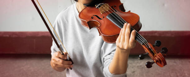 istock Violin was holding by woman hand,finger pressing on string and bow prepare for playing,blurry light around 1293618299