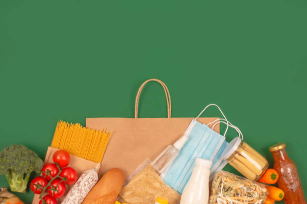 istock Composition with food and medicines donations on green background with copy space - pasta, fresh vegatables, canned food, baguette, cooking oil. Food bank concept. Flat lay, selective focus 1293618904