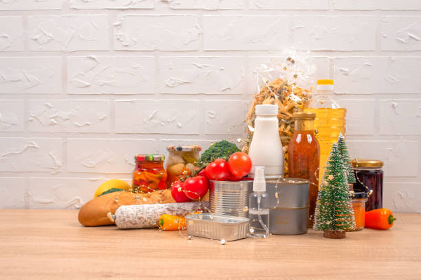 istock Christmas donations - food donations on light background with copyspace - pasta, fresh vegatables, canned food, baguette, cooking oil with Christmas decorations. Food bank. Selective focus 1293618907