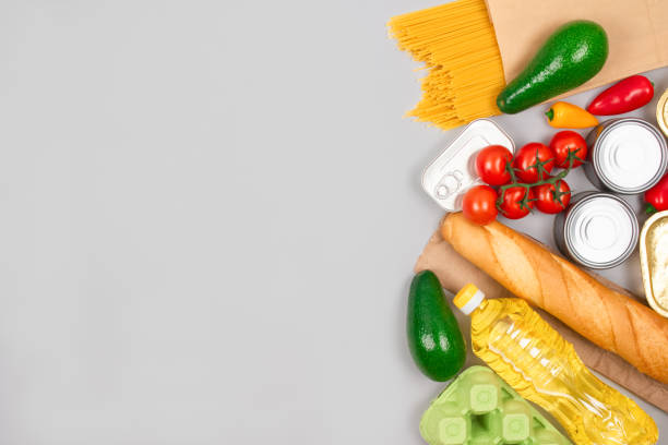 istock Flat lay composition with food donations on gray background with copyspace - pasta, fresh vegatables, canned food, baguette, cooking oil. Food donation and food bank concept 1293618929