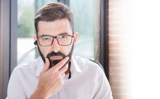 istock businessman looking at the camera and touching the beard 1293621372
