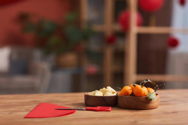 Preparations For Chinese New Year Conceptual no people shot of tangerines, fortune cookies and colored paper on table in living room decorated for Chinese New Year Celebration chinese new year photos stock pictures, royalty-free photos & images