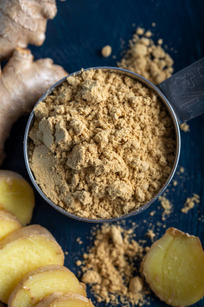 istock Fresh ginger root and ground ginger spice in black bowl on blue background. 1293624839