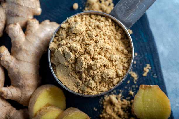istock Fresh ginger root and ground ginger spice in black bowl on blue background. 1293625552