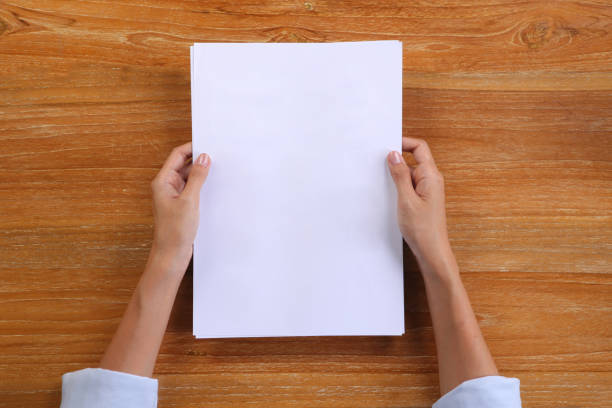 istock Top view hand holding A4 paper with wooden background 1293625697
