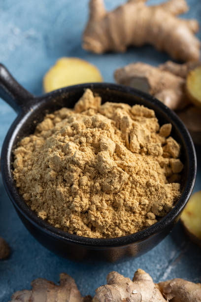 istock Fresh ginger root and ground ginger spice in black bowl on blue background. 1293625816