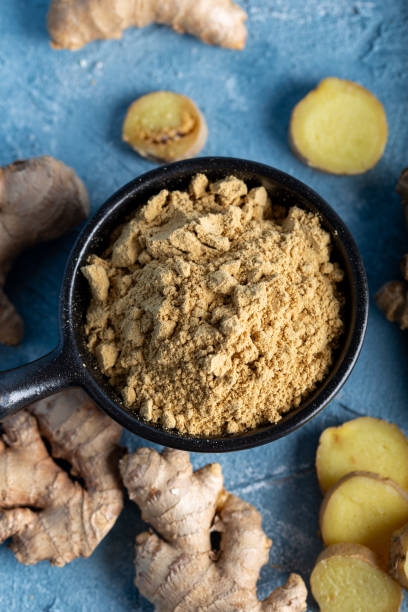 istock Fresh ginger root and ground ginger spice in black bowl on blue background. 1293626522
