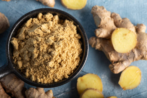 istock Fresh ginger root and ground ginger spice in black bowl on blue background. 1293626738