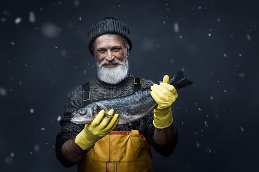 Portrait of senior fisherman holding big fish