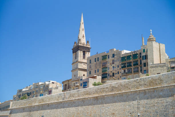 Fortification walls and historical architecture - Valletta, Malta Fortification walls and historical architecture, visible from the ferry between the Sliema district and the historical old town of Valletta - Valletta, Malta st paul cathedral la valletta malta island stock pictures, royalty-free photos & images