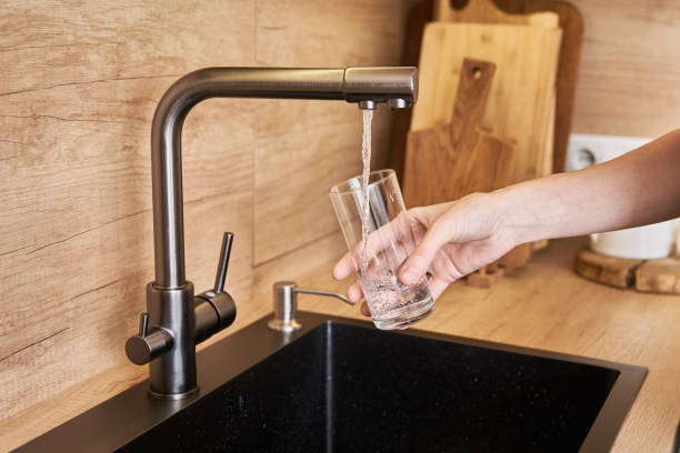 istock Woman pour clean water from tap filter into a glass 1293630723
