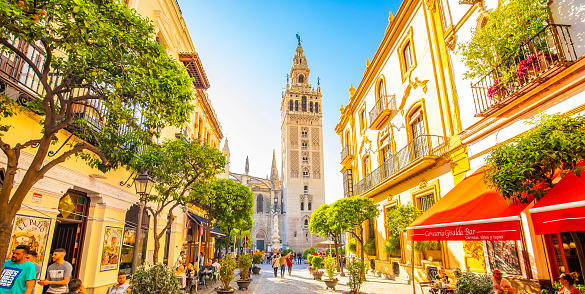 Sevilla, Spain - 6 March, 2020: Panoramic city view with Seville Cathedral and Giralda tower. Old town street Calle Mateos Gago.