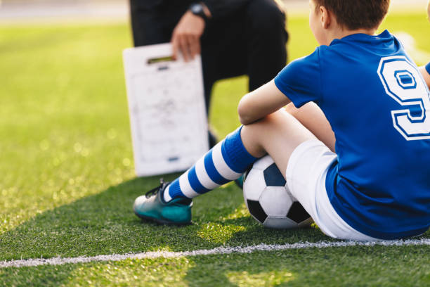 allenatore allenatore che insegna ai bambini sul campo di calcio. allenatore di calcio che allena i bambini. sessione di allenamento di calcio per bambini. educazione tattica calcistica. coach spiega una strategia di gioco usando il tabellone - american football football blackboard play foto e immagini stock