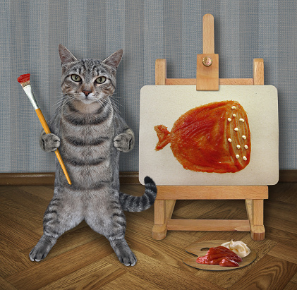 A gray cat  artist with a paintbrush paints a piece of sausage on a canvas on an easel in its art studio.