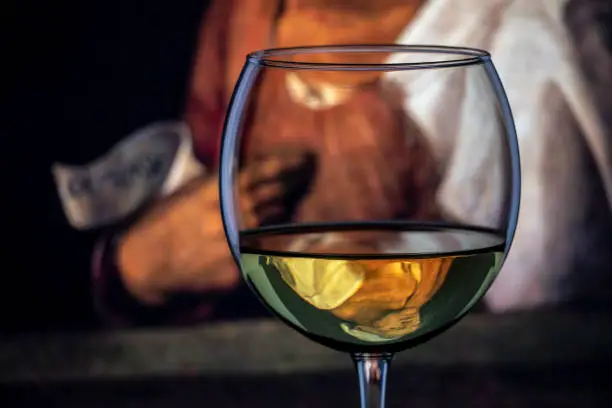 Photo of The classic portrait of the old woman by Italian artist Giorgione shown as inverted reflection in a wine goblet.