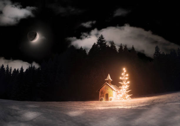 cappella innevata con albero di natale illuminato da solo nei boschi bui - luna crescente che sorge - snow chapel christmas germany foto e immagini stock