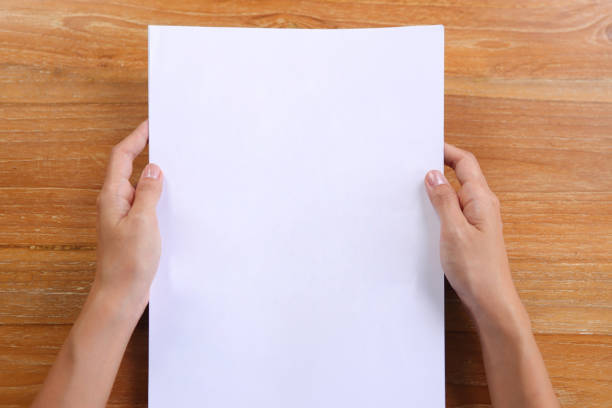 istock Top view hand holding A4 paper with wooden background 1293638119