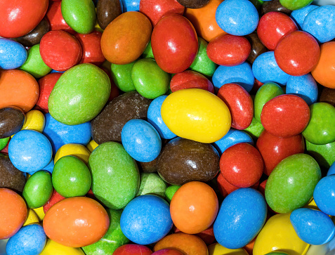 A series of multi-colored button-shaped chocolates. Macro photo perfect for Junk food.