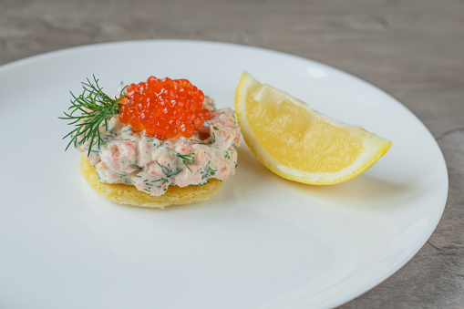 Toast skagen - classic Swedish appetizer. Sandwiches with shrimps and caviar on white plate. Nordic cuisine.