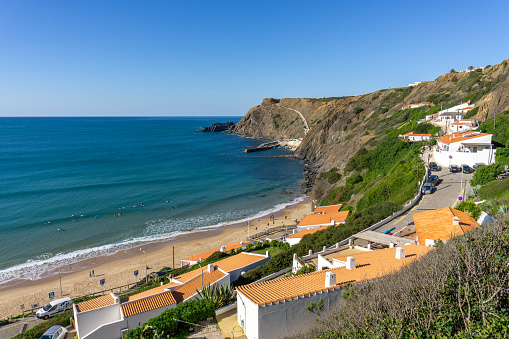 A view of the bay and village of Arrifana with many surfers in the water