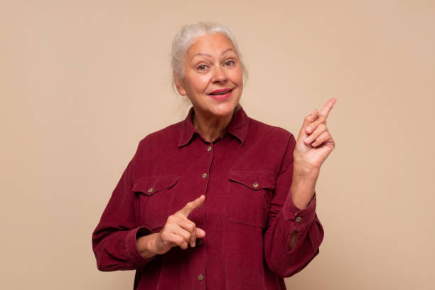 istock Amazed old woman pointing at copy space aside 1293649235