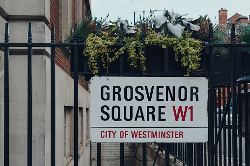 London, UK - December 5, 2020: Street name sign on a fence in Grosvenor Square, City of Westminster, a borough that occupies much of the central area of London including most of the West End.