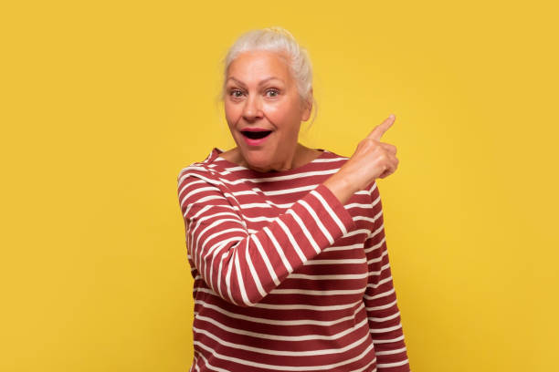 istock Amazed old woman pointing at copy space aside 1293649565