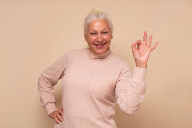 istock Senior woman doing ok gesture with hand smiling approving your choice. 1293650582
