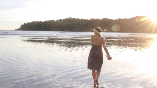 istock Woman walks down sandy beach at sunrise 1293651019