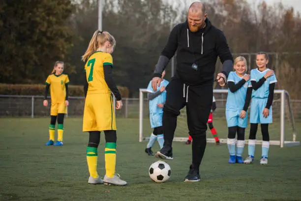 Photo of Soccer father coaching football daughter's team during a training session