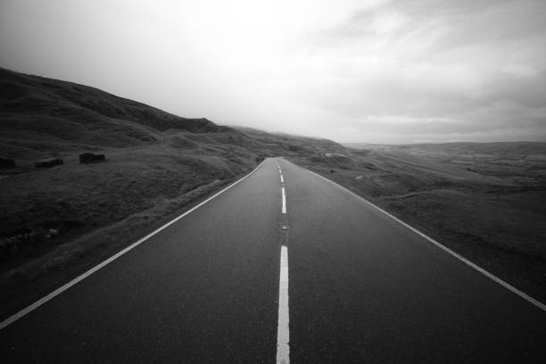 The long road ahead A great monochrome image of a long road middle of the road stock pictures, royalty-free photos & images