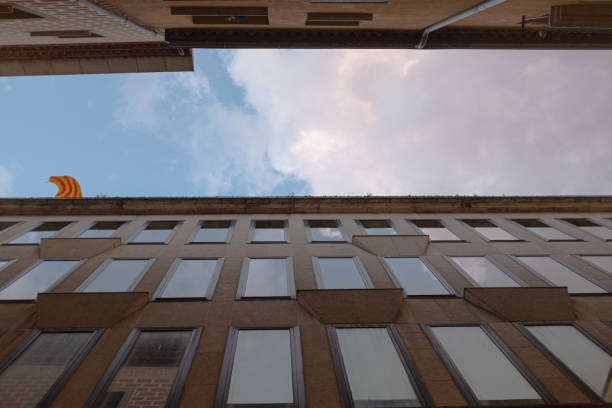 istock high building facade forced ground perspective with big glass mirror windows on a narrow street with a cloudy sky 1293655884