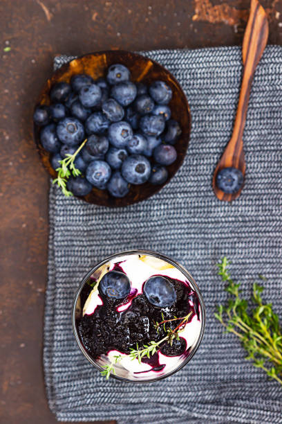 Dessert from mascarpone or ricotta cheese, blueberries and biscuit in glass on a dark background. No baked cheesecake or tiramisu. Top view. Dessert from mascarpone or ricotta cheese, blueberries and biscuit in glass on a dark concrete background. No baked cheesecake or tiramisu. Top view. yogurt fruit biscotti berry fruit stock pictures, royalty-free photos & images