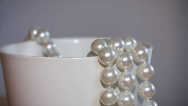 istock Few beads of pearls hanging on a white box on white background 1293661462