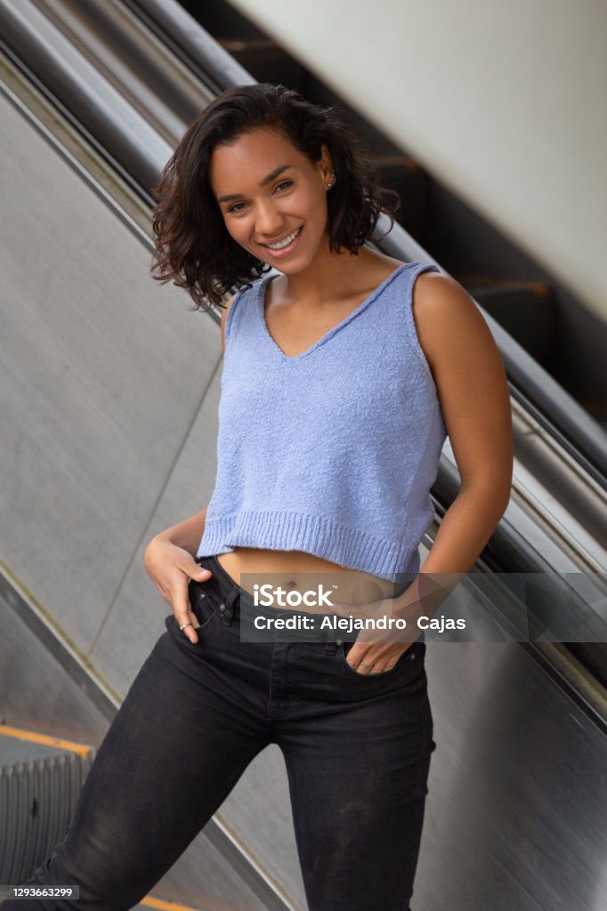 Cheerful Young Brunette Latina Girl With Short Hair With Curls Standing  Next To Electric Bleachers Wearing Blue Top Black Pants Casual Style Stock  Photo - Download Image Now - iStock