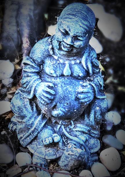 Miniature Laughing Buddha A miniature Laughing Buddha, also called “The Happy Buddha” graces a rock garden outside a Hoboken, New Jersey apartment building. The Laughing Buddha is said to attract good luck and abundance. laughing buddha garden statue stock pictures, royalty-free photos & images