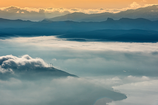Landscape shot of mountains and dramatic clouds mixed with fog in winter