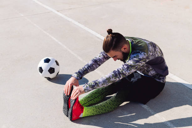 istock soccer player stretching legs sitting on the floor 1293671235