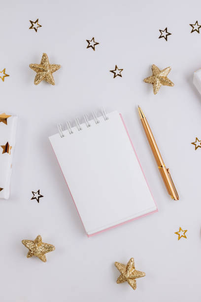istock Festive golden decorations and empty notebook on white background. Flat lay. Planning concept. 1293673862