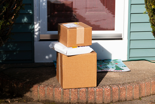 Three packages are delivered to the frint stoop of a residential house.